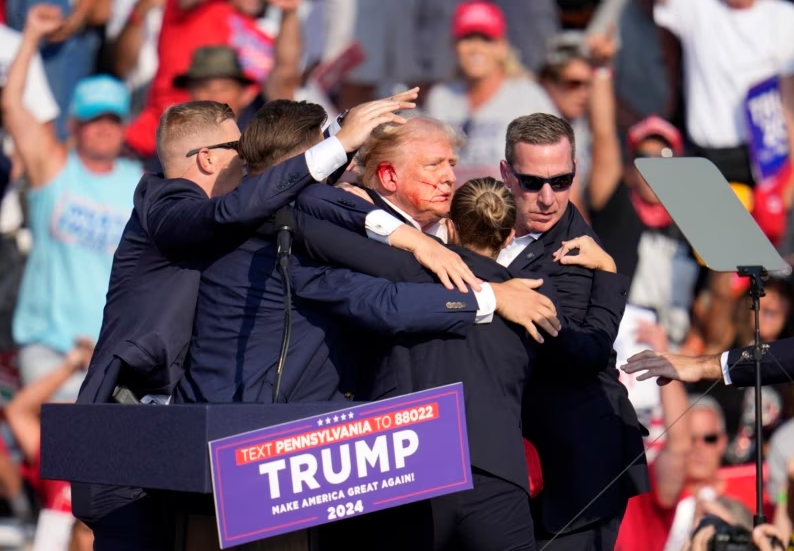 El candidato presidencial republicano y expresidente Donald Trump recibe ayuda para salir del escenario en un evento de campaña en Butler, Pensilvania, el 13 de julio de 2024.