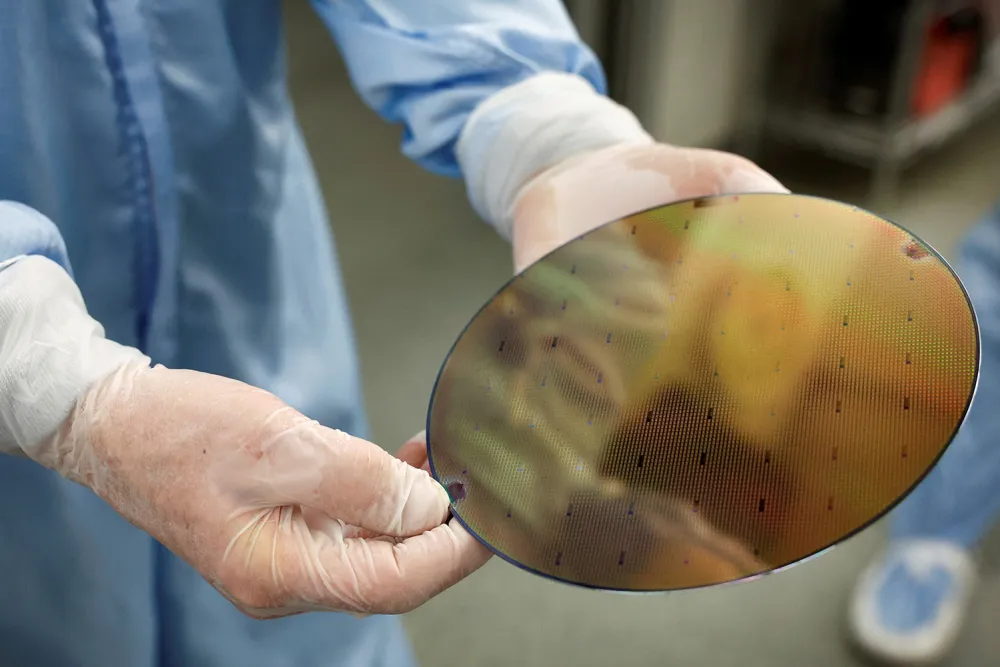 A worker displays a silicon wafer at a semiconductor computer chip fabrication plant in Nijmegen, Netherlands, on March 14. Piroschka van de Wouw/Reuters