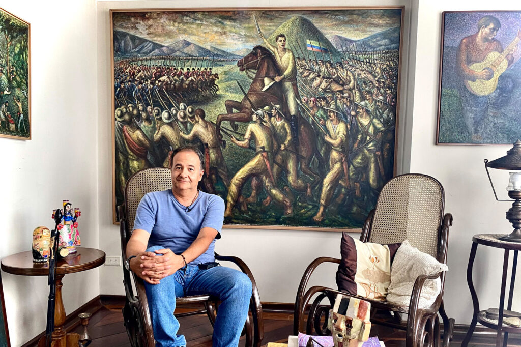 Ricardo Blandón Giraldo y al fondo el mural: Batalla del pantano de Vargas, pintado por Alipio Jaramillo Giraldo. Foto: Natalia López Arboleda, Unimedios Manizales.